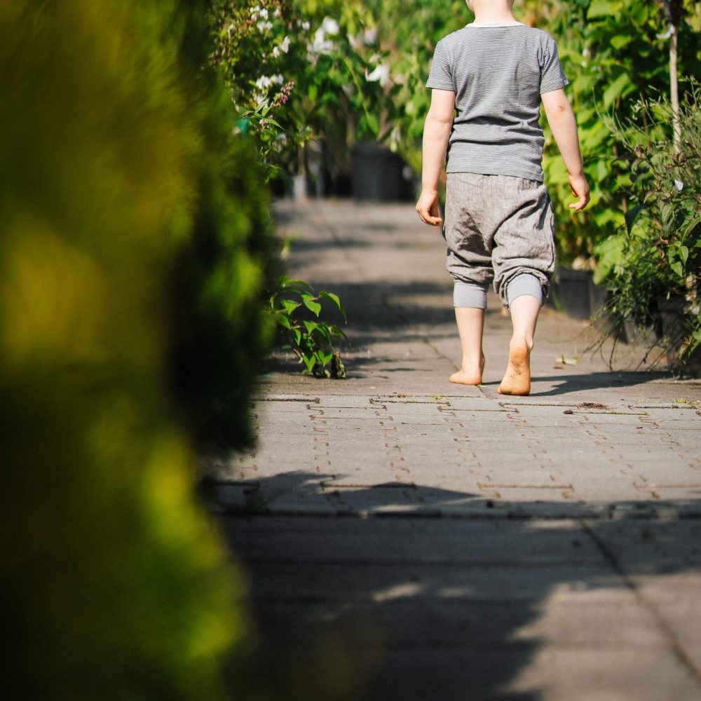 Kind läuft barfuß über einen Gartenweg